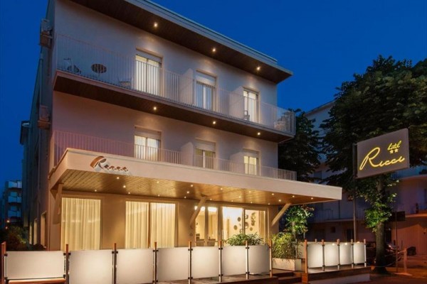 Budynek hotelowy wieczorem z zewnętrznym oświetleniem i balkonami.