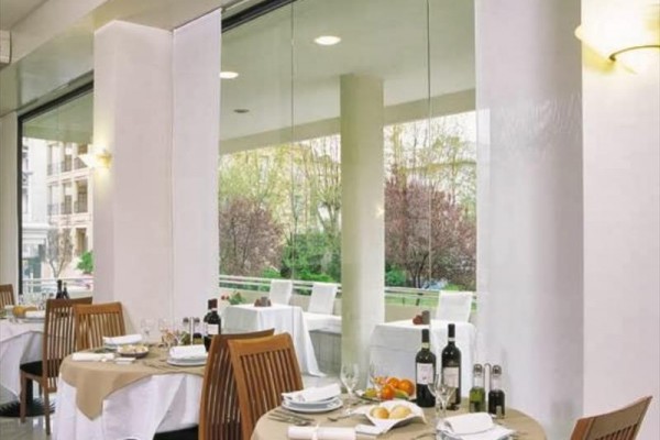 Luksusowa restauracja z nakrytymi stołami i dużymi oknami z widokiem na ogród.