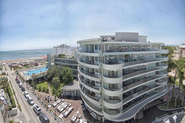 Nowoczesny hotel nad morzem z balkonami i dużym basenem obok plaży.