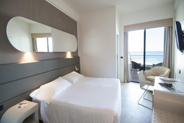 Nowoczesny pokój hotelowy z łóżkiem małżeńskim i widokiem na morze.