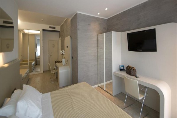 Nowoczesny pokój hotelowy z prostymi meblami, telewizorem i biurkiem.