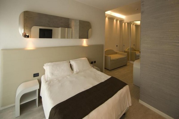 Nowoczesny pokój hotelowy z podwójnym łóżkiem i lustrami na ścianach.