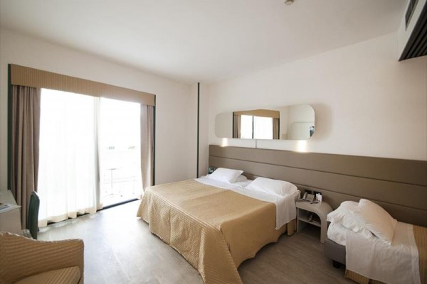 Pokój hotelowy z łóżkiem małżeńskim, dostawką i nowoczesnym wnętrzem.