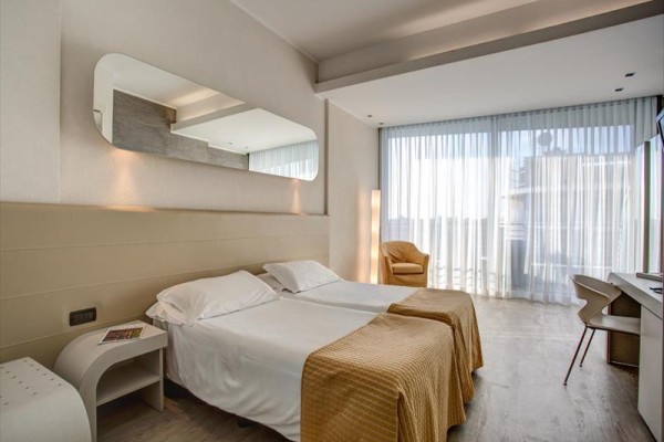 Nowoczesny pokój hotelowy z dwoma łóżkami, dużym oknem i biurkiem.
