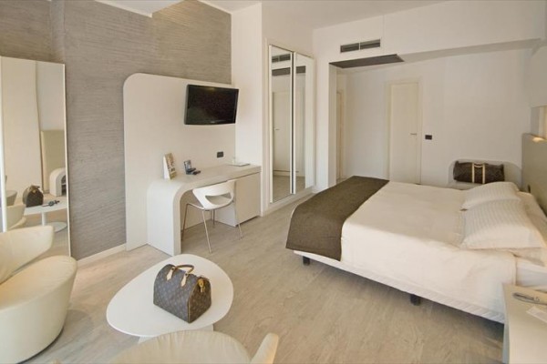 Nowoczesny pokój hotelowy z łóżkiem, biurkiem i fotelem.