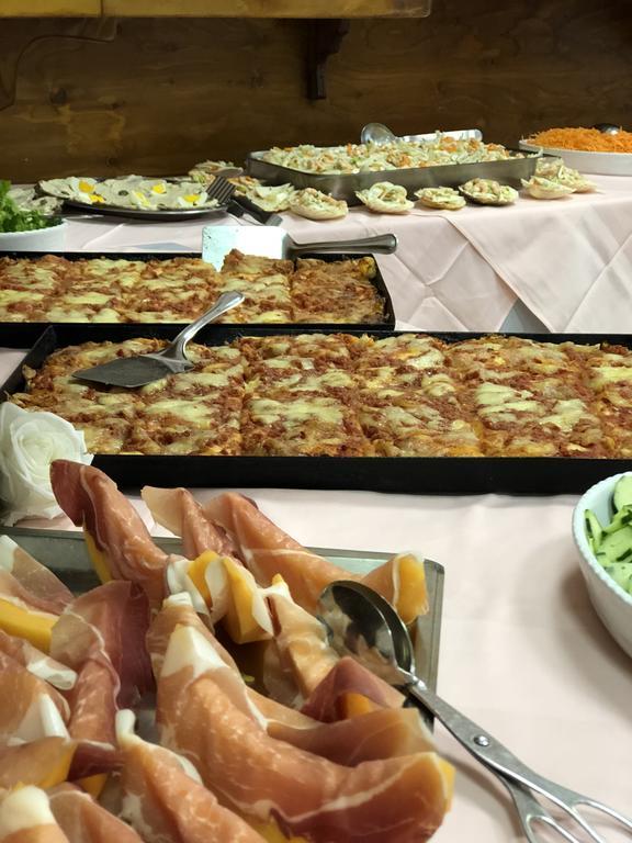 Stół pełen jedzenia, w tym talerze z szynką i pizzą.