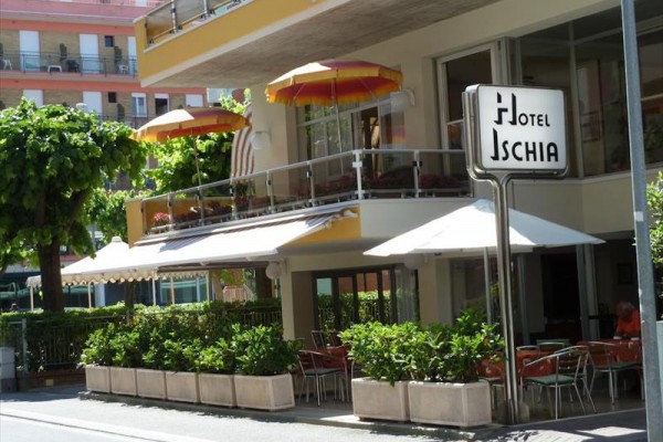 Hotel Ischia z zewnętrznymi miejscami do siedzenia i kolorowymi parasolami.