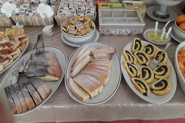 Desery i wypieki na talerzach z pakowanymi dżemami i herbatą w tle.