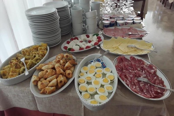 Bogaty bufet śniadaniowy z jajkami, pieczywem, wędlinami, serami i jogurtami.