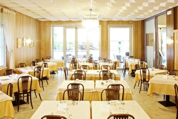 Restauracja z drewnianymi ścianami, nakrytymi stołami i krzesłami.