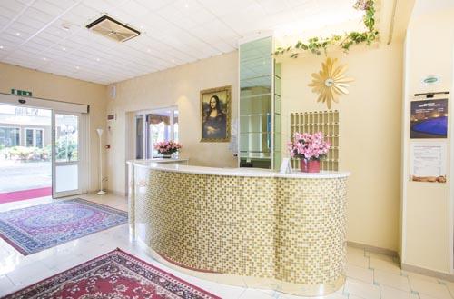 Recepcja hotelowa z mozaikowym blatem, kwiatami i obrazem na ścianie.