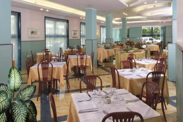 Przestronna restauracja z nakrytymi stolikami i drewnianymi krzesłami.