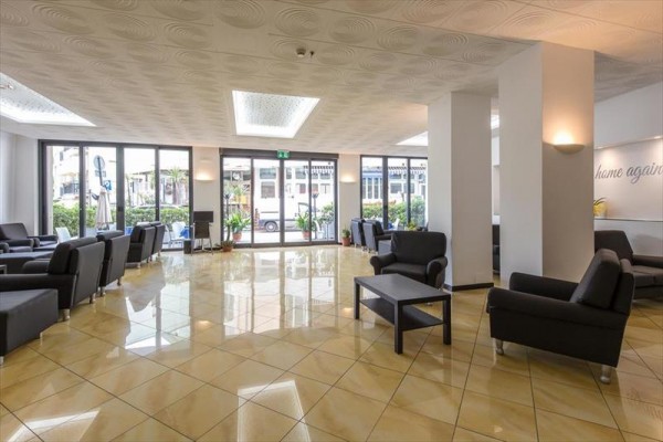 Nowoczesne lobby z czarnymi fotelami i dużymi oknami.