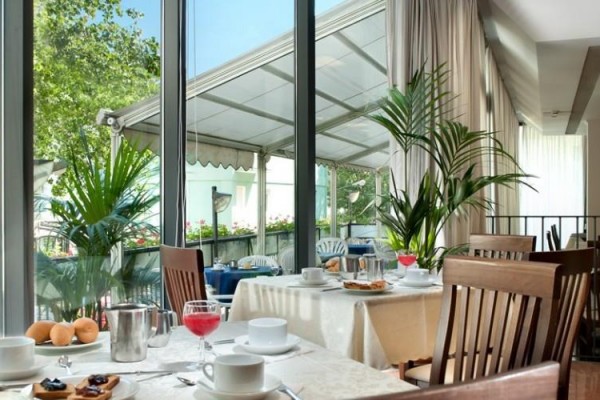 Restauracja z drewnianymi stołami i widokiem na zewnętrzny taras.