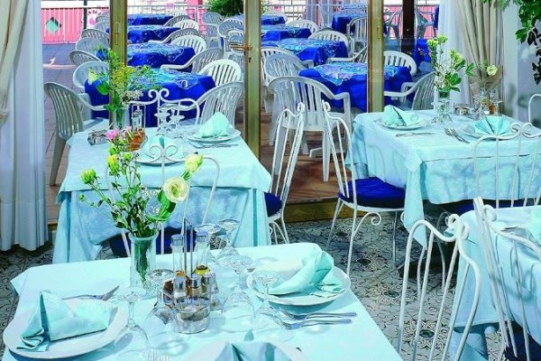 Elegancko nakryte wnętrze restauracji z widokiem na taras i morze.