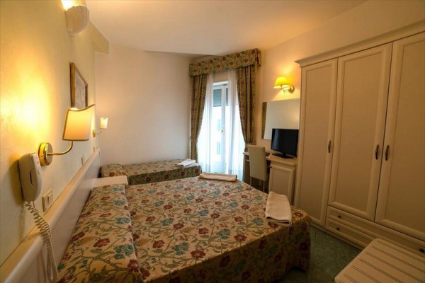 Pokój hotelowy z dwoma łóżkami, telewizorem i szafą.