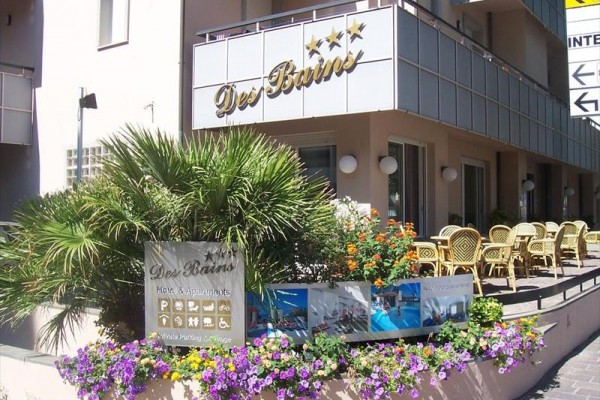 Wejście do hotelu Des Bains z zewnętrznymi siedzeniami i dekoracjami kwiatowymi.