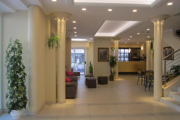 Hol hotelowy z kanapą, recepcją i roślinami.