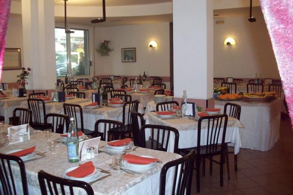 Restauracja z nakrytymi stołami i czarnymi krzesłami.