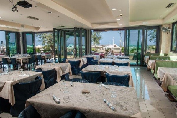 Restauracja z nakrytymi stołami i widokiem na zewnętrzny taras.