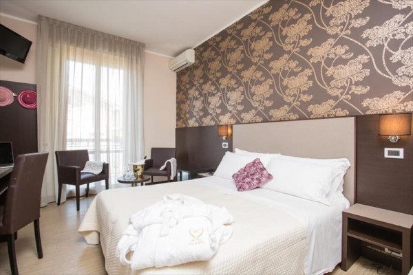 Nowoczesny pokój hotelowy z łóżkiem małżeńskim, tapetą w kwiaty i balkonem.