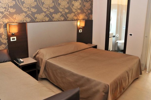 Pokój hotelowy z łóżkiem małżeńskim i przyległą łazienką.