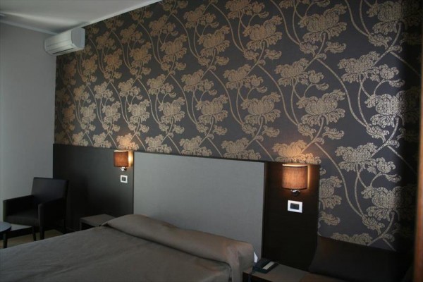 Nowoczesny pokój hotelowy z luksusową tapetą w kwiaty na ścianie i tapicerowanym łóżkiem.