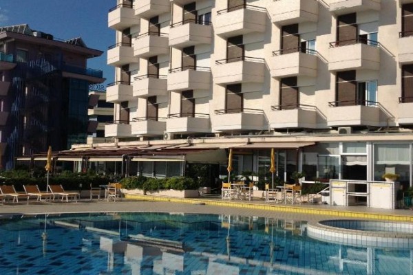 Hotel z balkonami i basenem na pierwszym planie.
