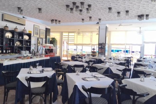 Restauracja z nakrytymi stołami, ciemnymi krzesłami i dekoracjami na ścianach.