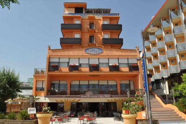 Pięciopiętrowy pomarańczowy hotel z barem na parterze i miejscami do siedzenia na zewnątrz.