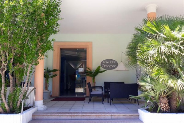 Wejście do hotelu Ombrosa otoczone zielenią i zewnętrznymi siedzeniami.