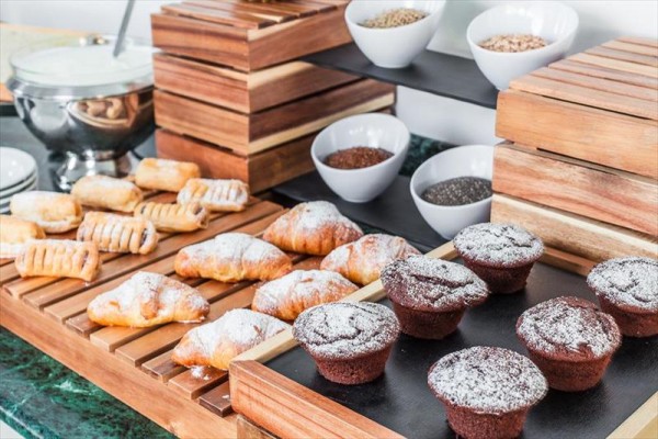 Wypieki z cukrem, muffiny i miski z nasionami na drewnianym stojaku.