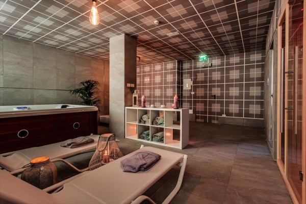 Pomieszczenie wellness z leżakami, wanną z hydromasażem i sauną w nowoczesnym stylu.  
