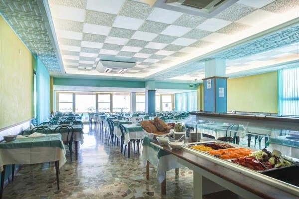 Pusta restauracja z rzędami stołów i bufetem z jedzeniem na pierwszym planie.