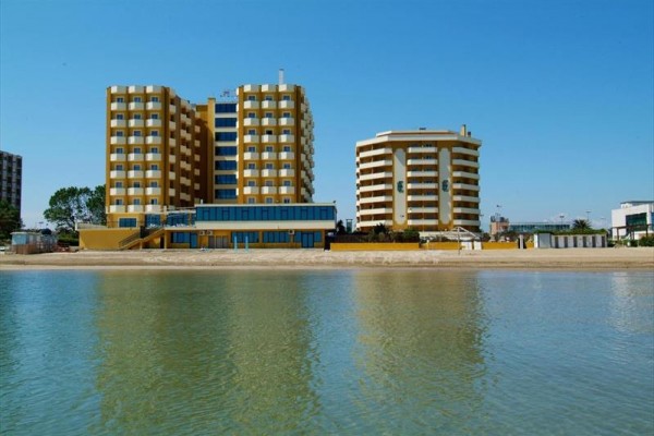 Dwa żółte nowoczesne budynki nad morzem z piaszczystą plażą.