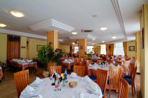 Elegancko nakryta restauracja z okrągłymi stołami i drewnianymi krzesłami.