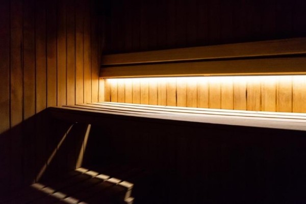 Drewniane wnętrze sauny oświetlone ciepłym światłem.