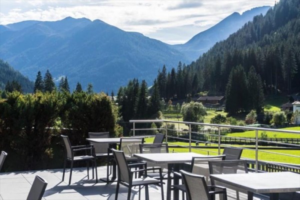 Taras z zewnętrznymi stolikami i widokiem na góry.