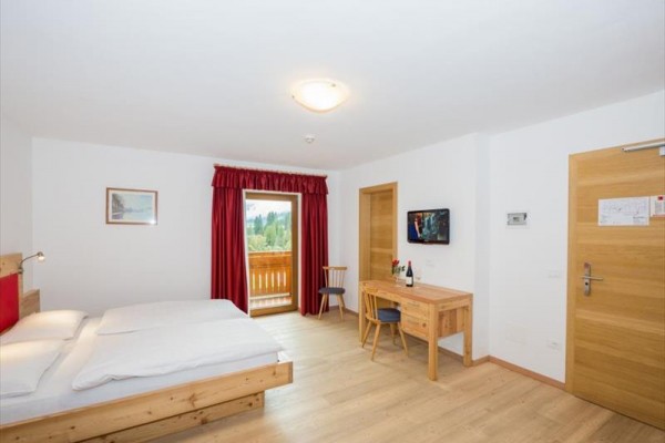 Pokój hotelowy z podwójnym łóżkiem, biurkiem i oknem balkonowym.