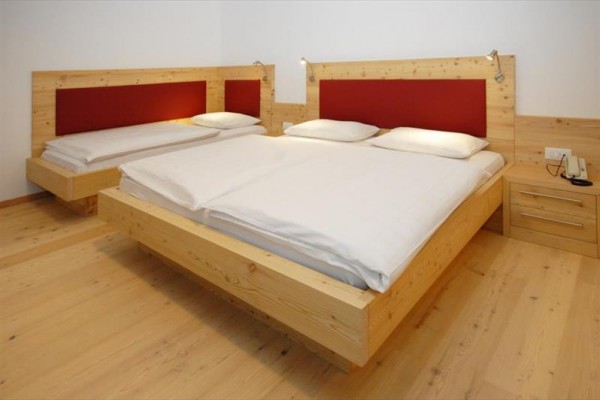 Pokój z dwoma drewnianymi łóżkami z białą pościelą i czerwonymi zagłówkami.