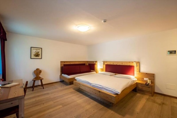 Pokój hotelowy z łóżkiem małżeńskim, sofą i drewnianymi meblami.