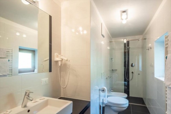 Nowoczesna łazienka z umywalką, toaletą i przeszklonym prysznicem.