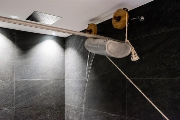 Zawieszone metalowe urządzenie z dwoma krążkami i liną nad płytkami w łazience.