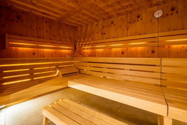 Wnętrze drewnianej sauny z ławkami i delikatnym oświetleniem.
