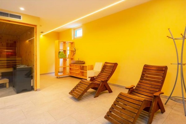 Pokój relaksacyjny z dwoma drewnianymi leżakami i sauną.