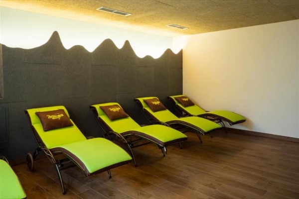 Rząd zielonych leżaków z brązowymi poduszkami w nowoczesnej strefie relaksu.