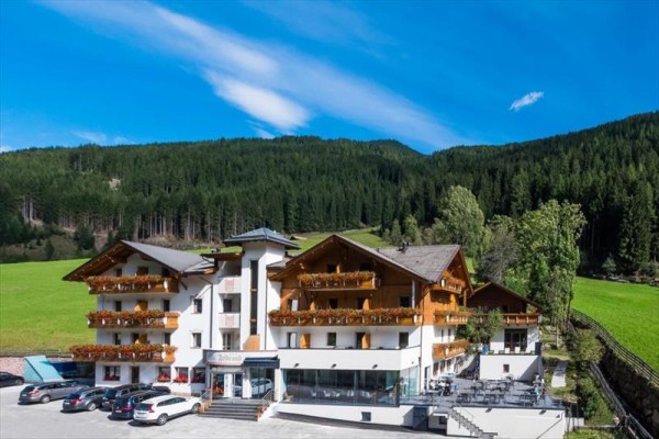 Hotel otoczony zielonymi łąkami i lasami w słoneczny dzień.