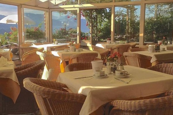 Przestronna restauracja z wiklinowymi krzesłami i widokiem na góry.
