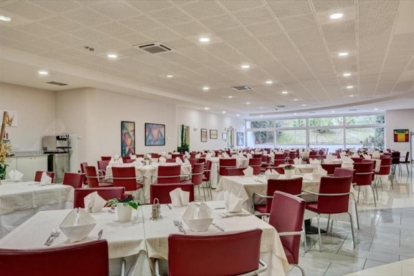 Jadalnia z czerwonymi krzesłami i białymi obrusami, gotowa na gości.