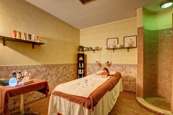 Pokój masażowy z leżanką do masażu i półkami z kosmetykami.